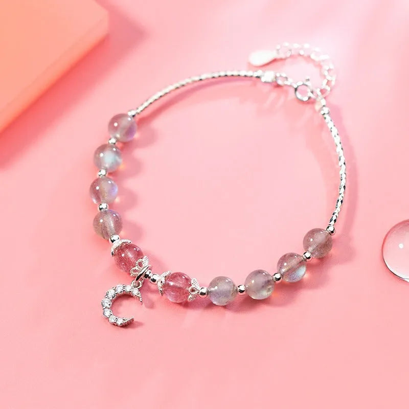 Handmade adjustable moonstone bracelet with crescent moon charm and crystal pendant on wrist