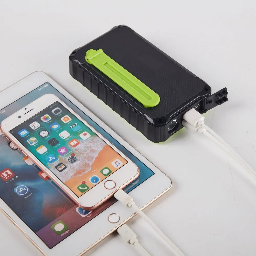 Orange hand solar mobile power bank showing USB ports, solar panel, and hand charging mechanism