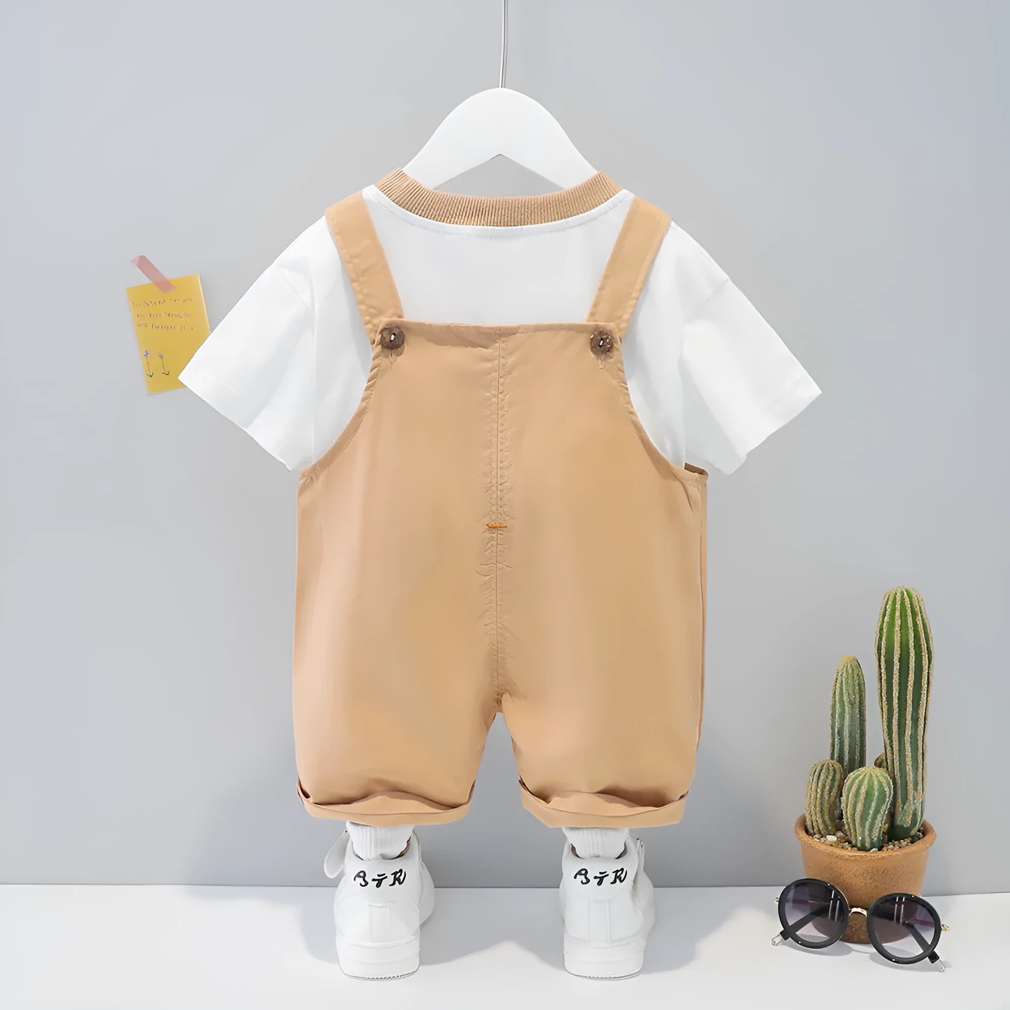 Cotton baby overalls with cartoon print in khaki colour, showing front opening with straps and short sleeves
