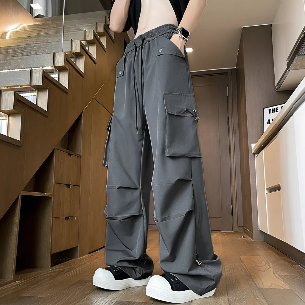 Women's plus size straight-leg waterproof trousers in black on a hanger, showing drawstring waist detail.