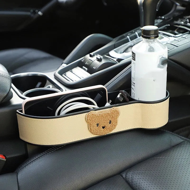 Leather car seat gap storage box with cartoon bear design, shown fitted next to a car seat.