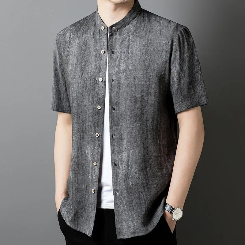 Man wearing a loose grey short sleeve cardigan shirt with a stand collar.