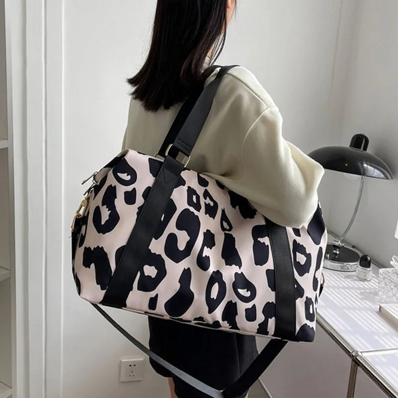 Women's large travel duffel bag with cow pattern, black, showing zippered main compartment and soft handle