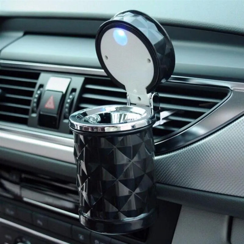 Black car ashtray made of ABS plastic hanging from a car air outlet vent.