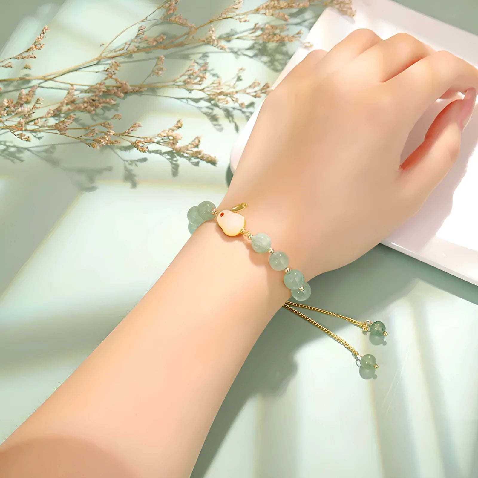 Rabbit charm bracelet with green natural stone beads and gold accents on adjustable chain