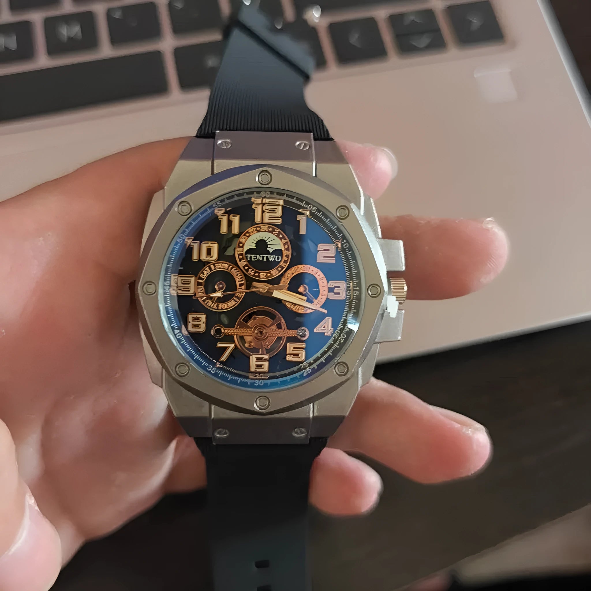 Four-ring Black And Silver Watch on a surface showing round black dial and interlocking metal bracelet