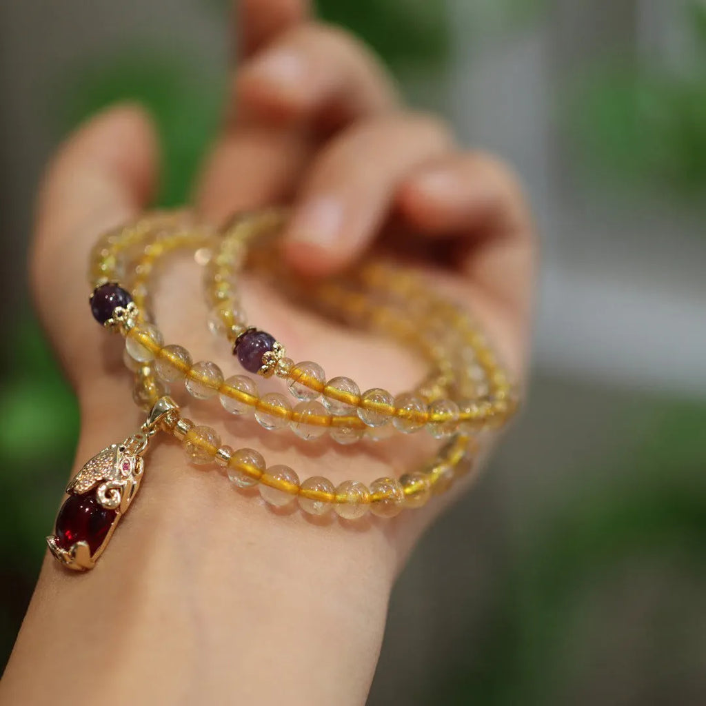 Gold rutilated quartz bracelet with three circles design and hanging chopsticks on wrist
