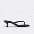 Black women's mid-heel sandals with a round toe and flip-toe strap on a white background