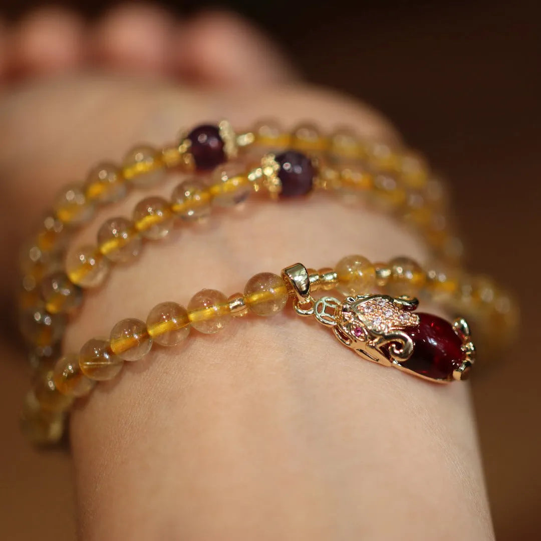 Gold rutilated quartz bracelet with three circles design and hanging chopsticks on wrist
