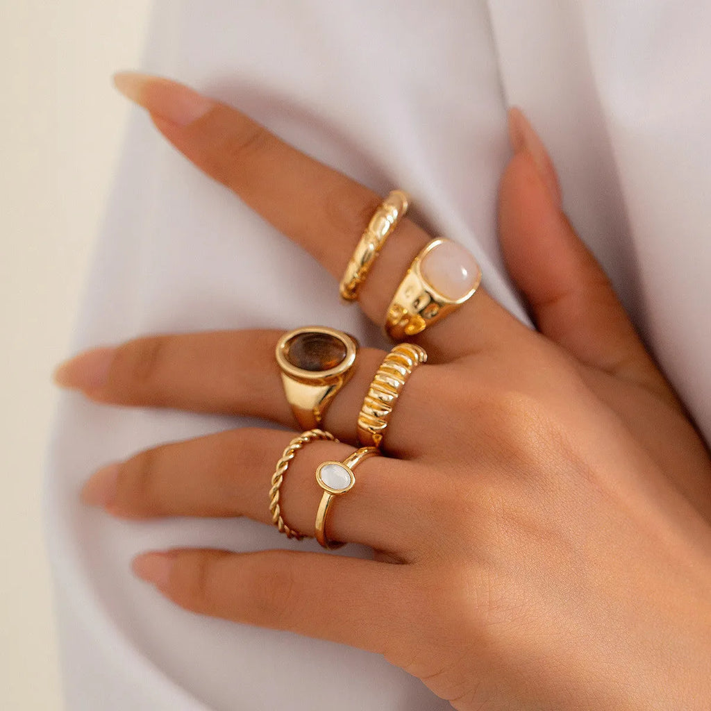 Six light gold geometric alloy rings arranged as a set showing geometric shapes and round elements