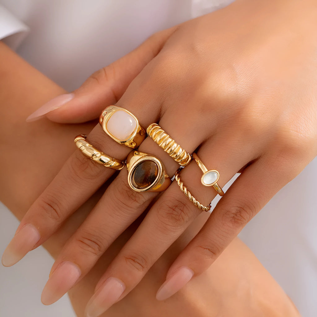 Six light gold geometric alloy rings arranged as a set showing geometric shapes and round elements