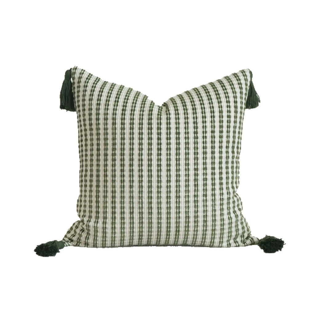 Green cotton and linen hotel pillow with striped or leaf pattern tassel detail on a bed.