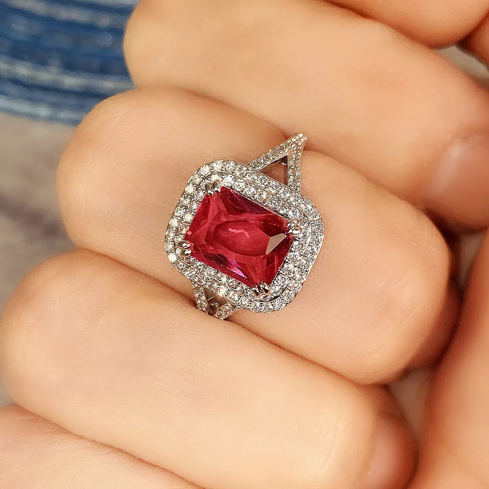 Women's copper square ring with red finish and a central rhinestone, showing geometric design.