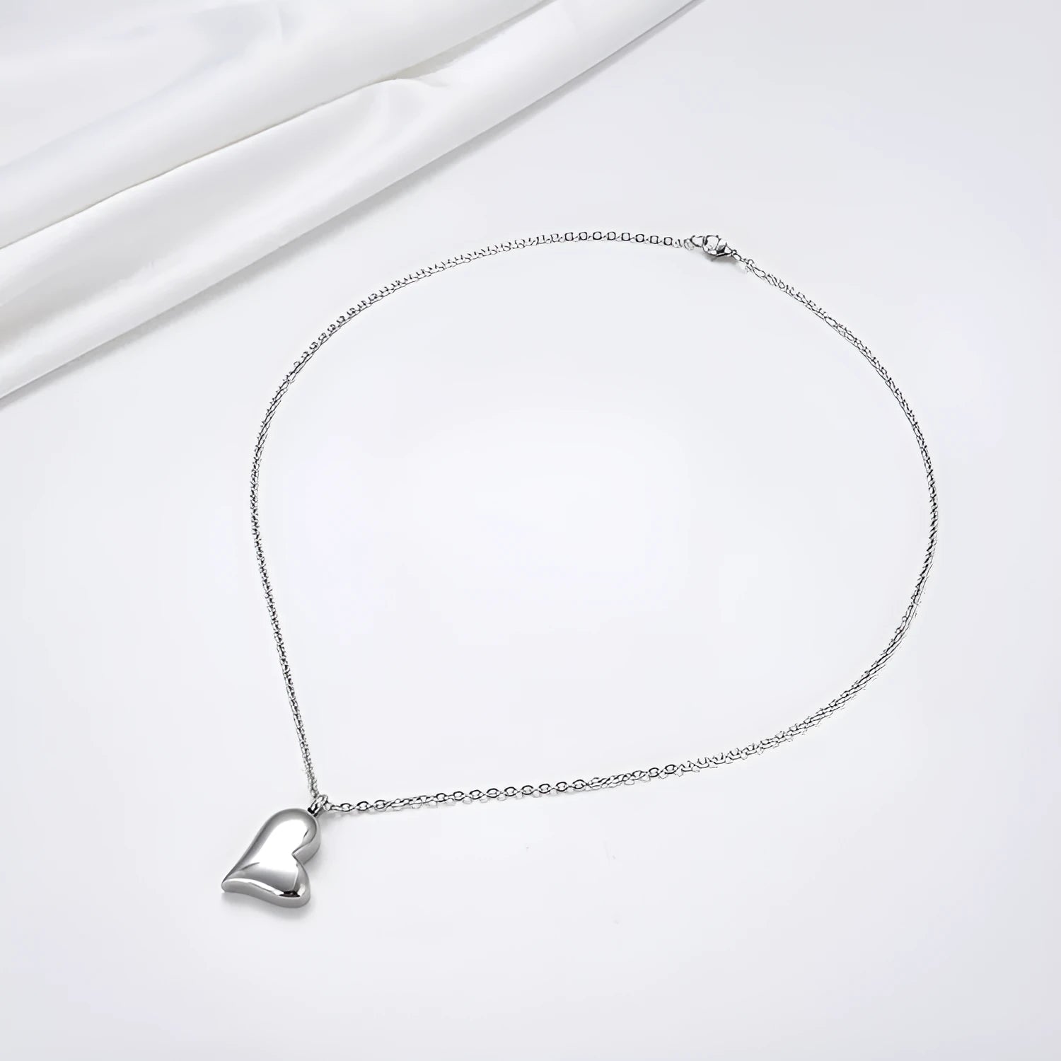 Silver curved peach heart pendant necklace on a stainless steel chain with extension.