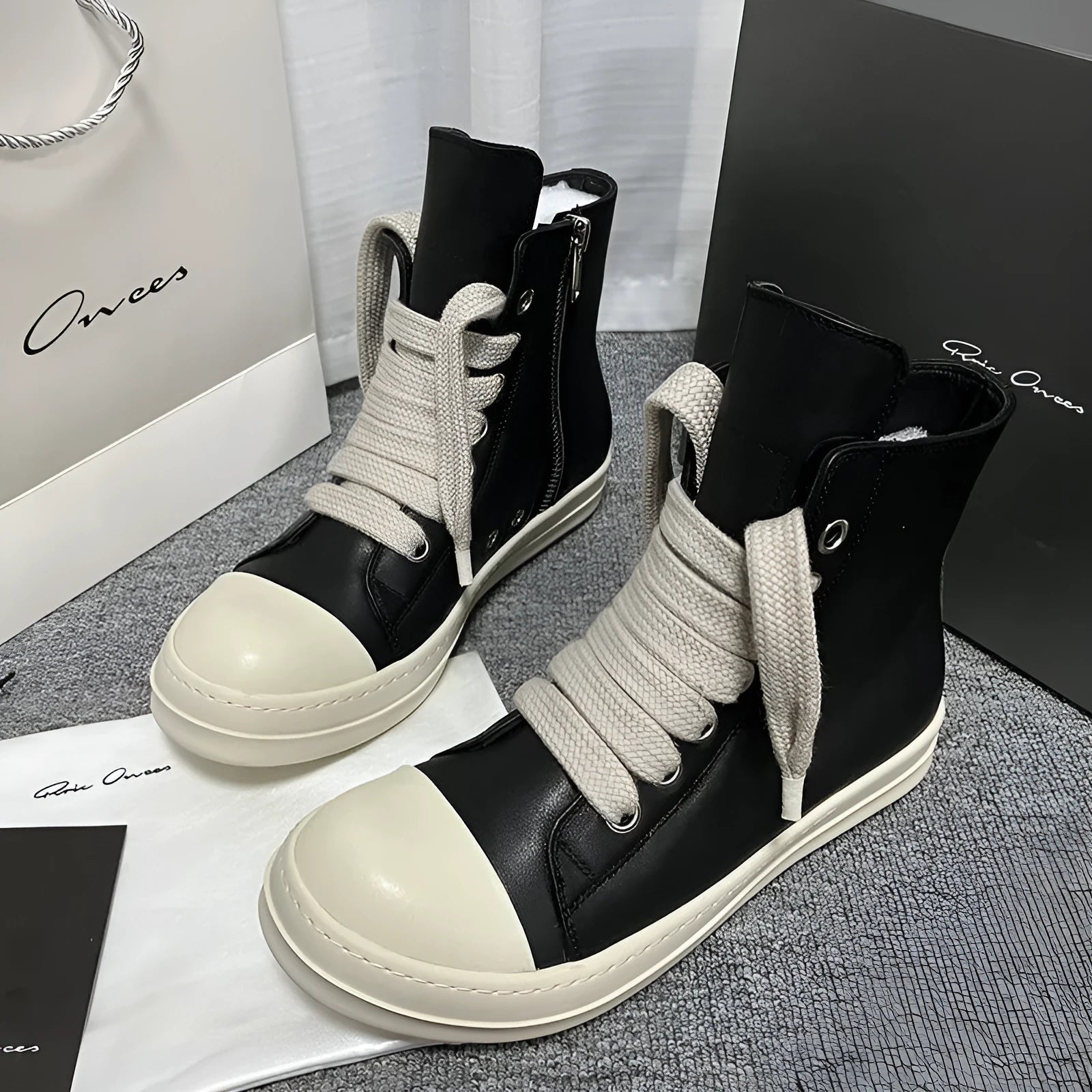 Black high-top leather sneakers with a side zipper and round toe on a rubber sole.