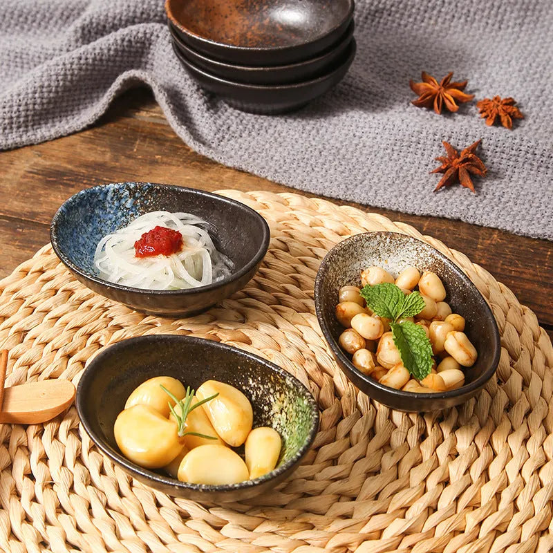 Oval Japanese ceramic sauce dipping bowl with underglaze pattern, shown on table setting