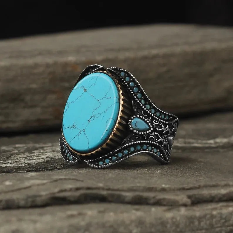 Men's antique silver alloy ring with a round shape and turquoise-coloured centrepiece on a grey background.
