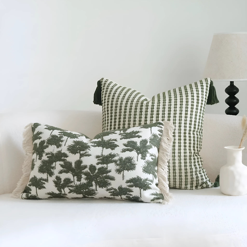 Green cotton and linen hotel pillow with striped or leaf pattern tassel detail on a bed.