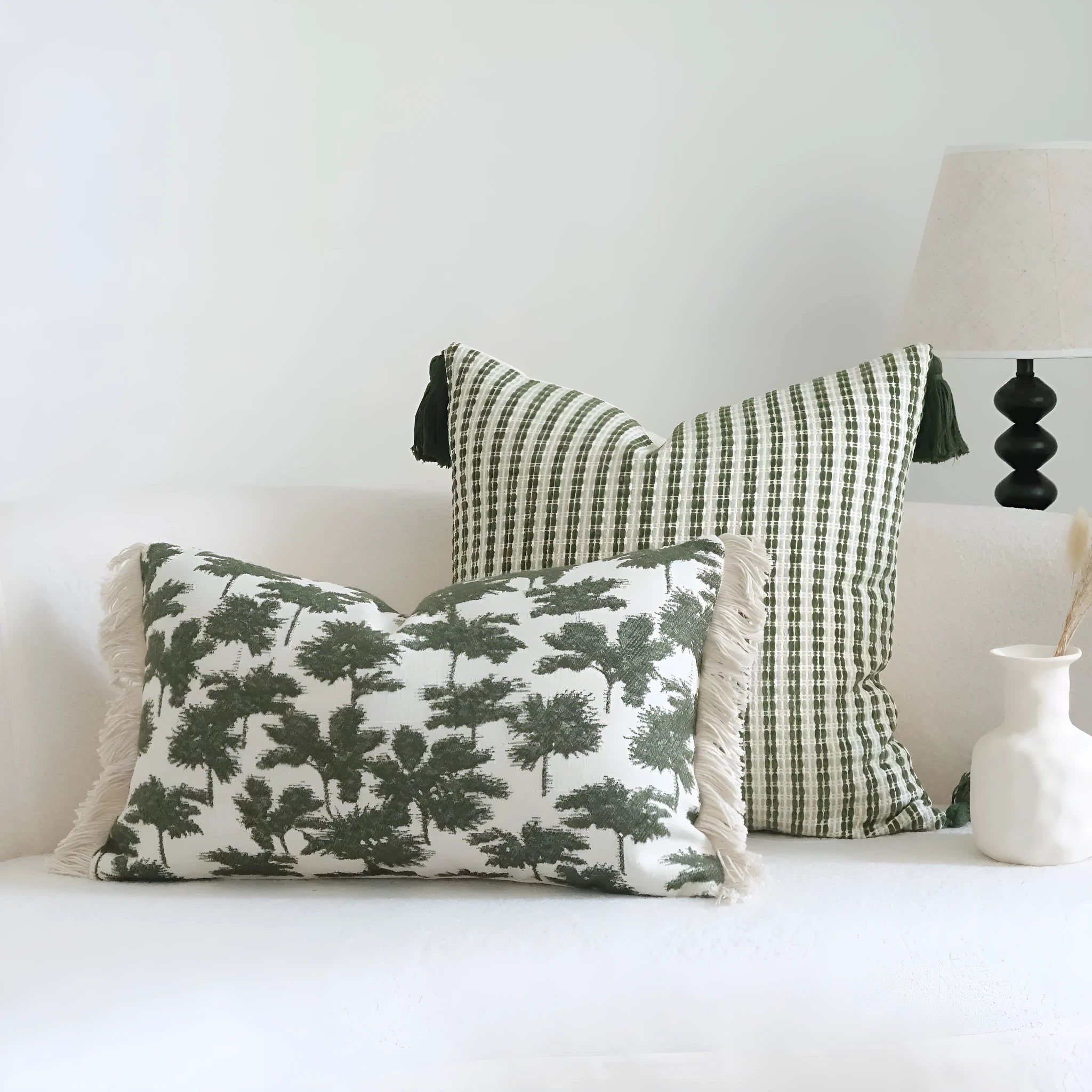 Green cotton and linen hotel pillow with striped or leaf pattern tassel detail on a bed.