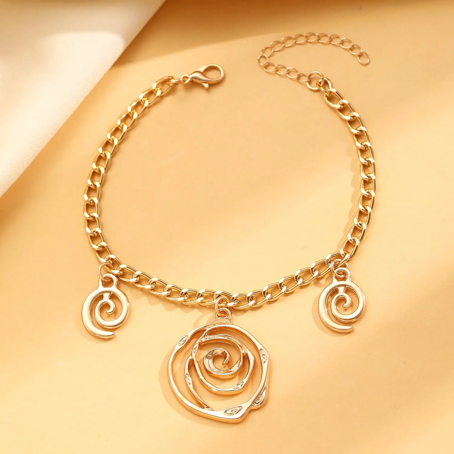 Gold tone spiral donut necklace, bracelet, and earrings set on a white background