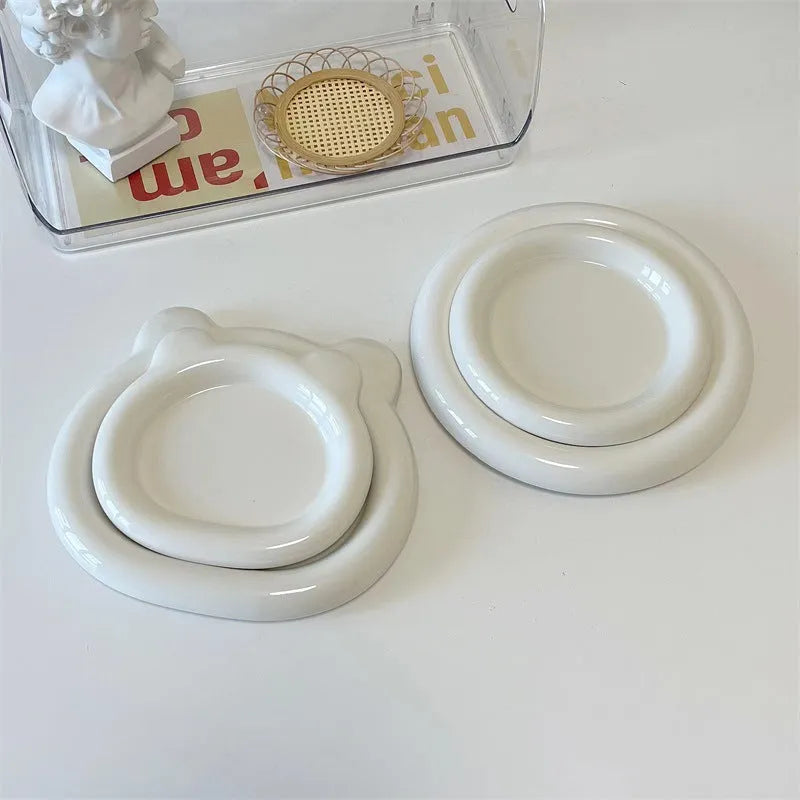 White round porcelain plant plate with a bear doodle design, shown under a small succulent pot.