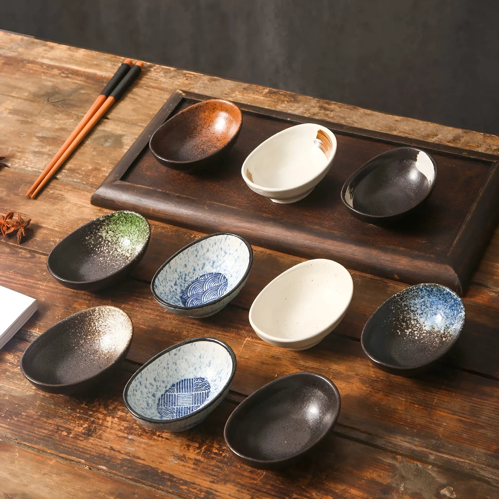 Oval Japanese ceramic sauce dipping bowl with underglaze pattern, shown on table setting