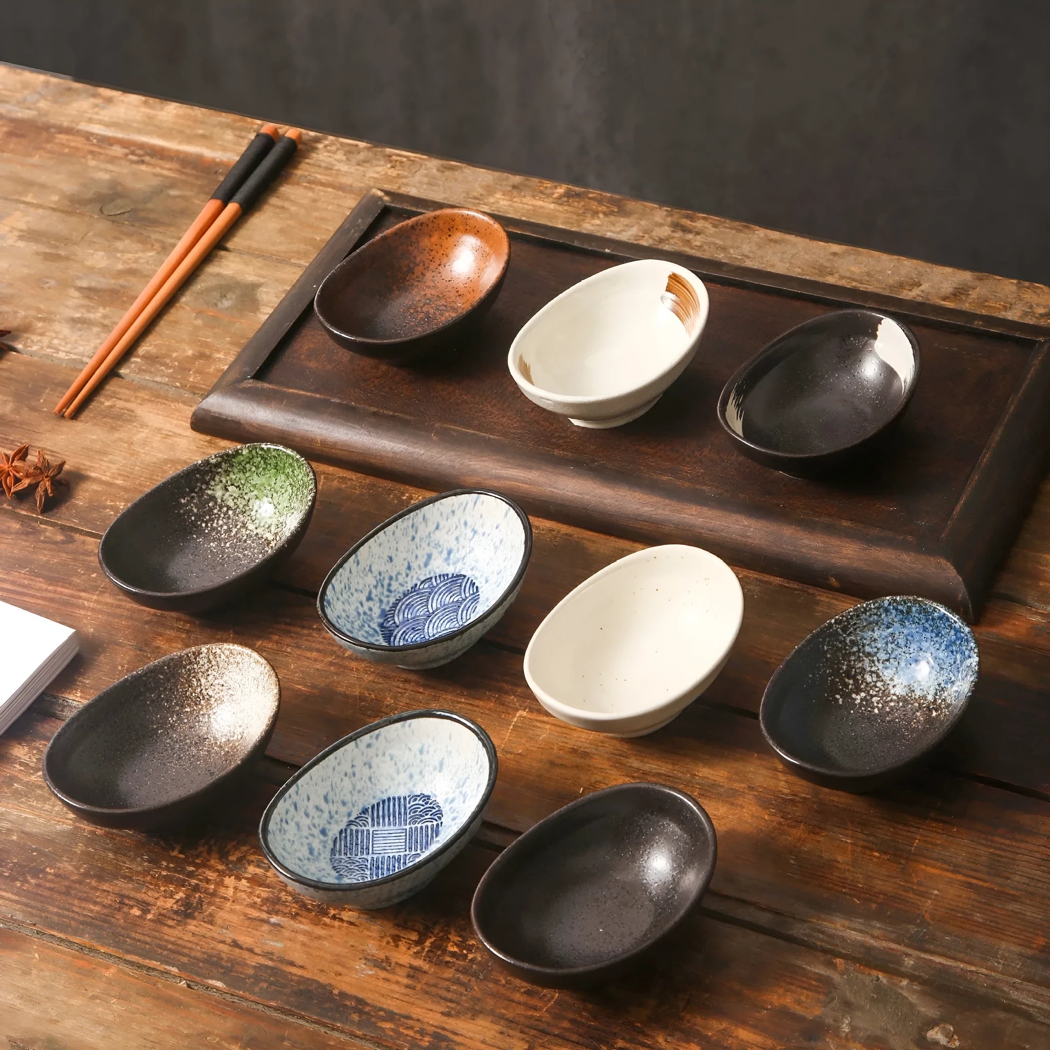Oval Japanese ceramic sauce dipping bowl with underglaze pattern, shown on table setting