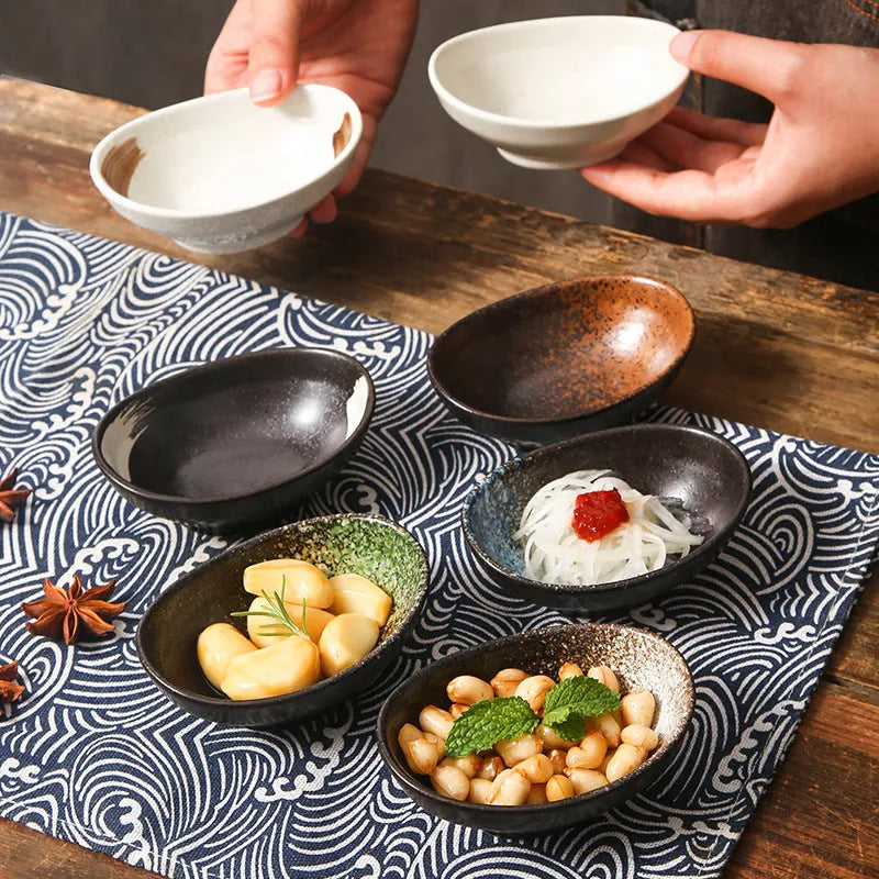 Oval Japanese ceramic sauce dipping bowl with underglaze pattern, shown on table setting