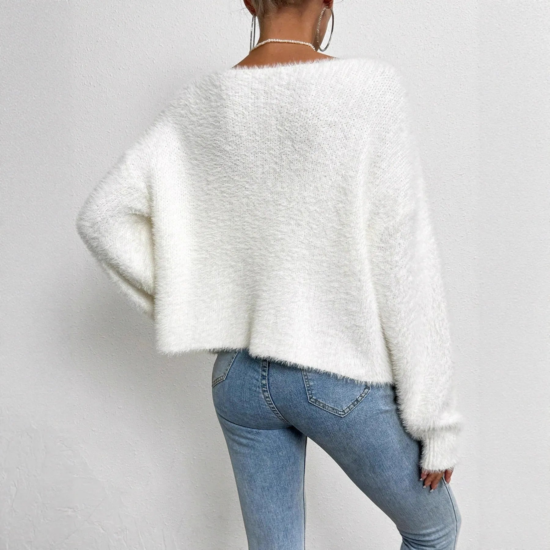 White women's V-neck polyester cardigan on a hanger, showing solid colour and knit texture.