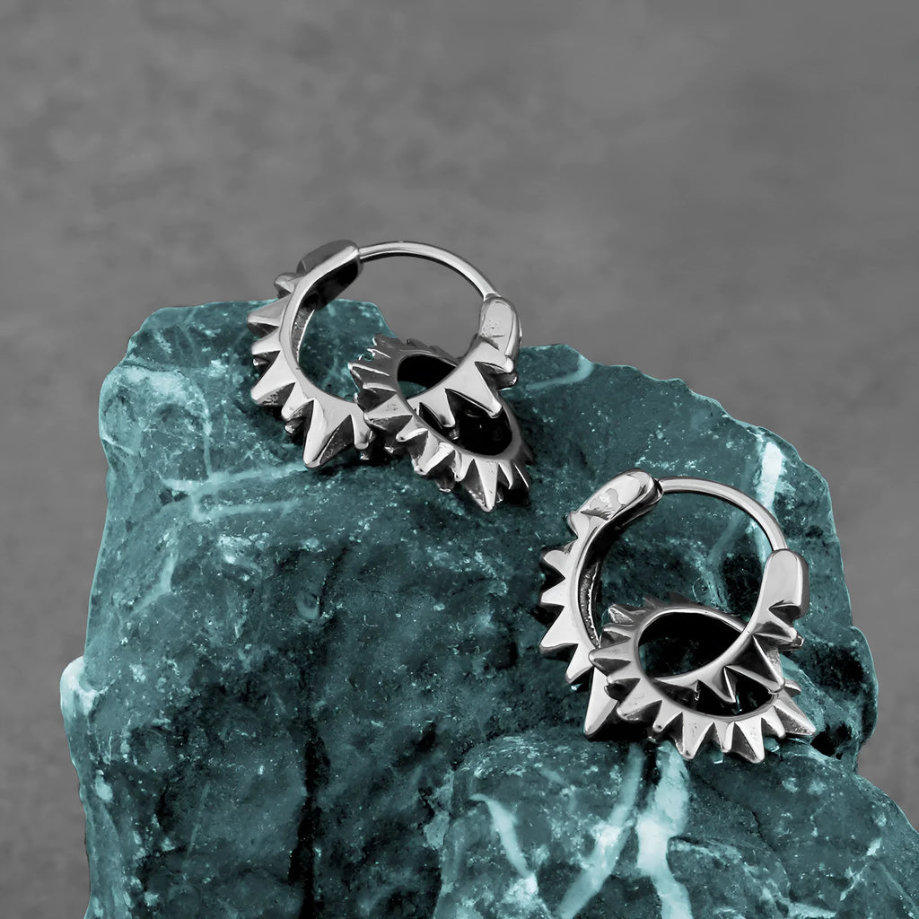 A pair of polished stainless steel round hoop earrings on a simple background.