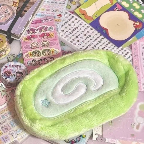 Soft velvet pencil case with Swiss roll cake design, rolled up.