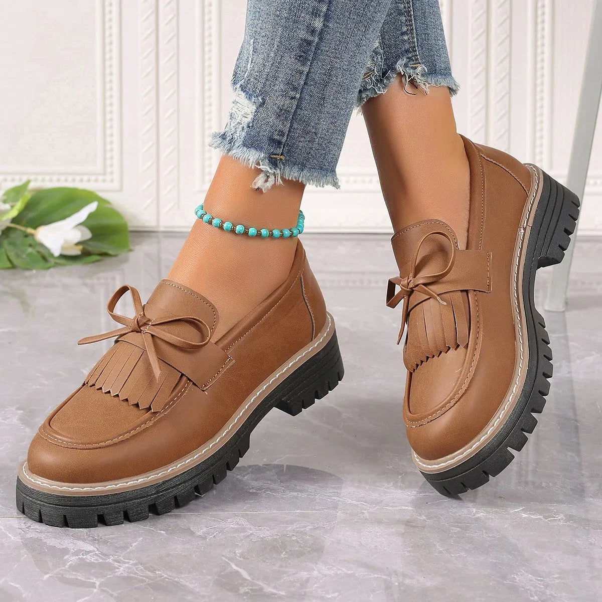 Black plus size women's loafers with a tassel and bowknot detail on a chunky flat rubber sole.