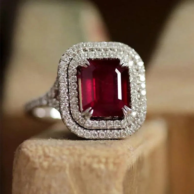 Women's copper square ring with red finish and a central rhinestone, showing geometric design.