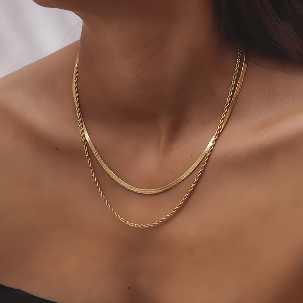 Close-up of a silver geometric double-layer twist pendant on a textured snake bones chain necklace.