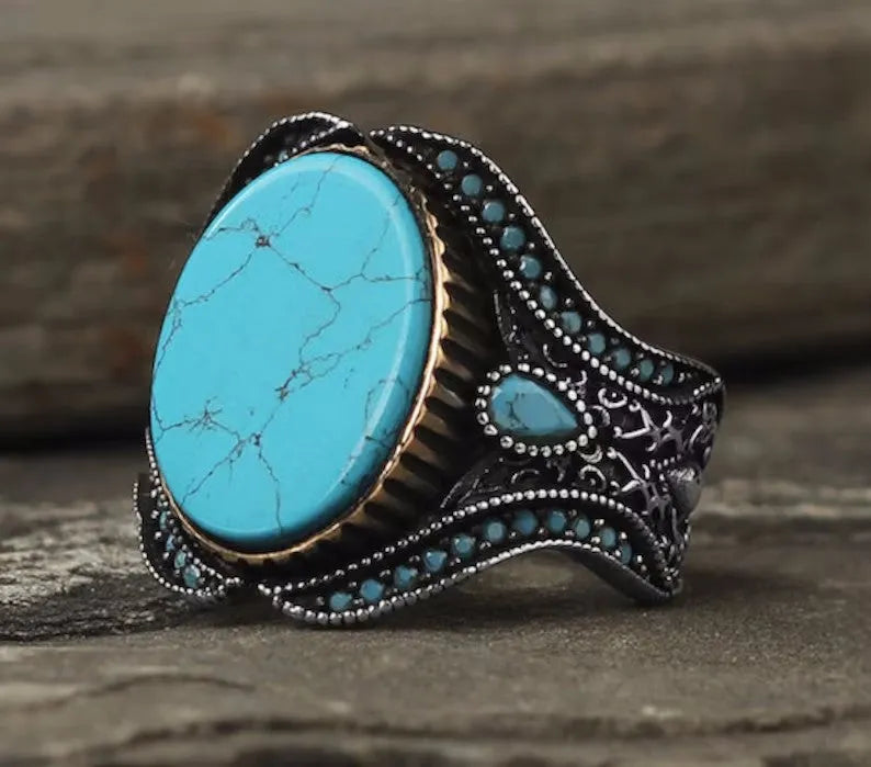 Men's antique silver alloy ring with a round shape and turquoise-coloured centrepiece on a grey background.