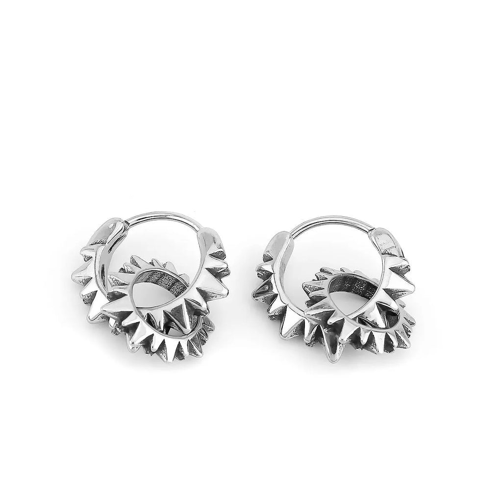 A pair of polished stainless steel round hoop earrings on a simple background.
