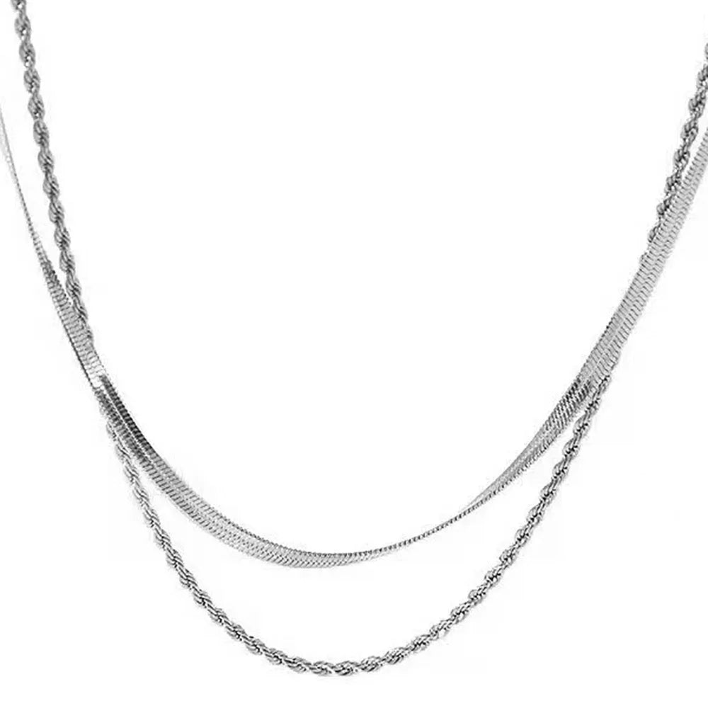 Close-up of a silver geometric double-layer twist pendant on a textured snake bones chain necklace.