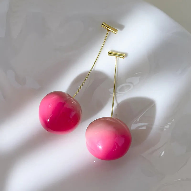 A pair of peach-shaped acrylic earrings on copper posts, shown in small and large size variants.