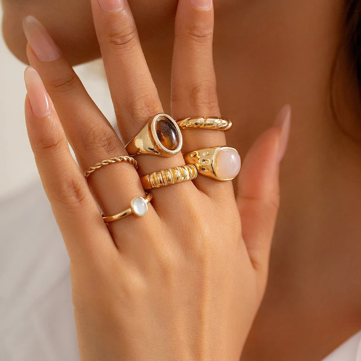 Six light gold geometric alloy rings arranged as a set showing geometric shapes and round elements