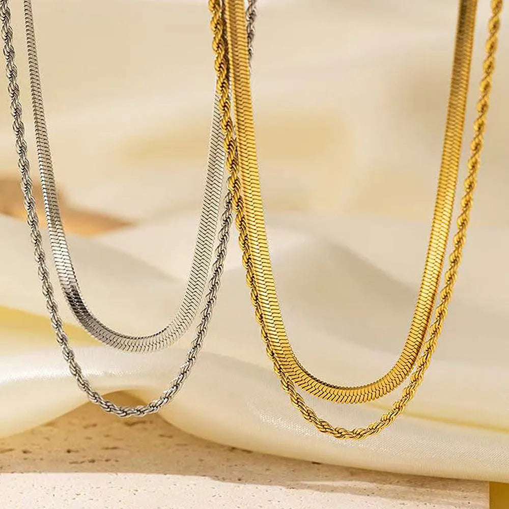 Close-up of a silver geometric double-layer twist pendant on a textured snake bones chain necklace.