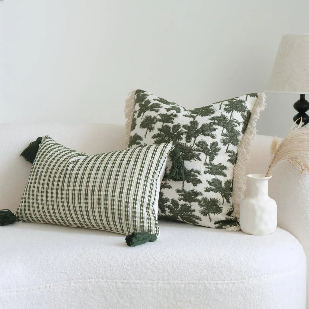 Green cotton and linen hotel pillow with striped or leaf pattern tassel detail on a bed.