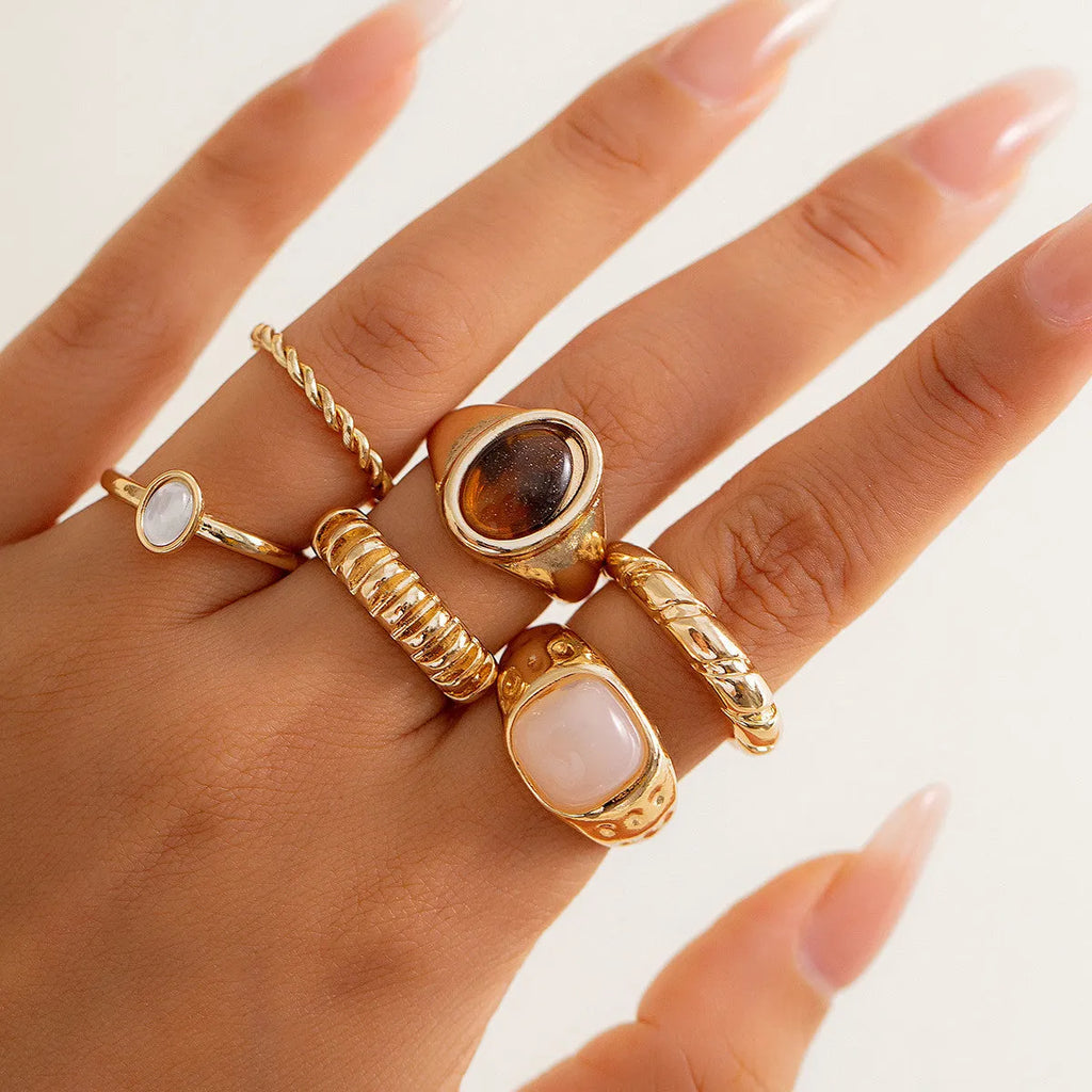 Six light gold geometric alloy rings arranged as a set showing geometric shapes and round elements
