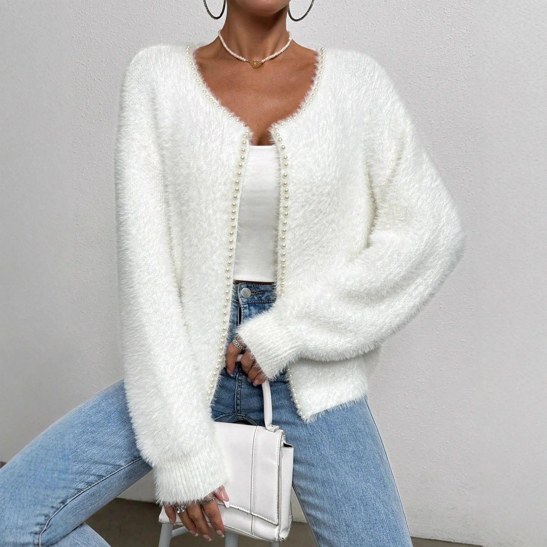 White women's V-neck polyester cardigan on a hanger, showing solid colour and knit texture.