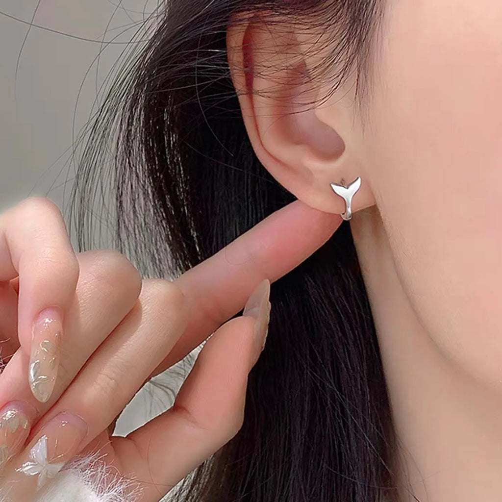 A pair of simple fishtail design earrings with a metallic electroplated finish in either white gold or yellow gold colour.