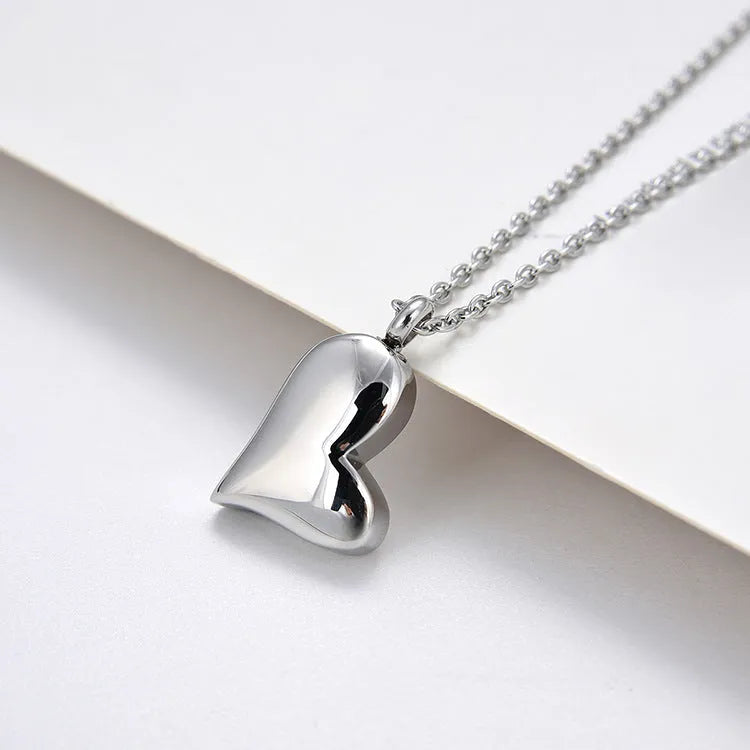 Silver curved peach heart pendant necklace on a stainless steel chain with extension.