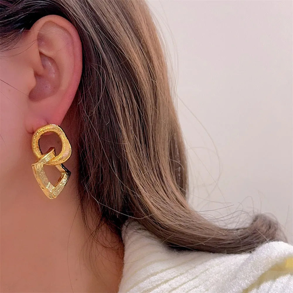 Gold and silver geometric circle pendant earrings with a 3.4cm drop length on a white background.