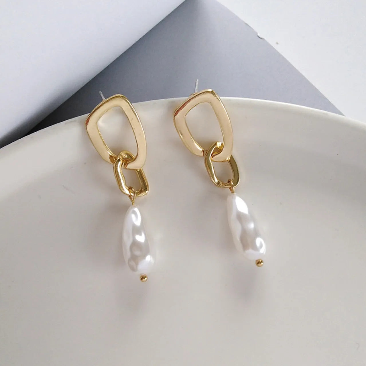 Gold copper irregular French pearl pendant earrings with geometric-shaped drop, 5 cm length, on white background