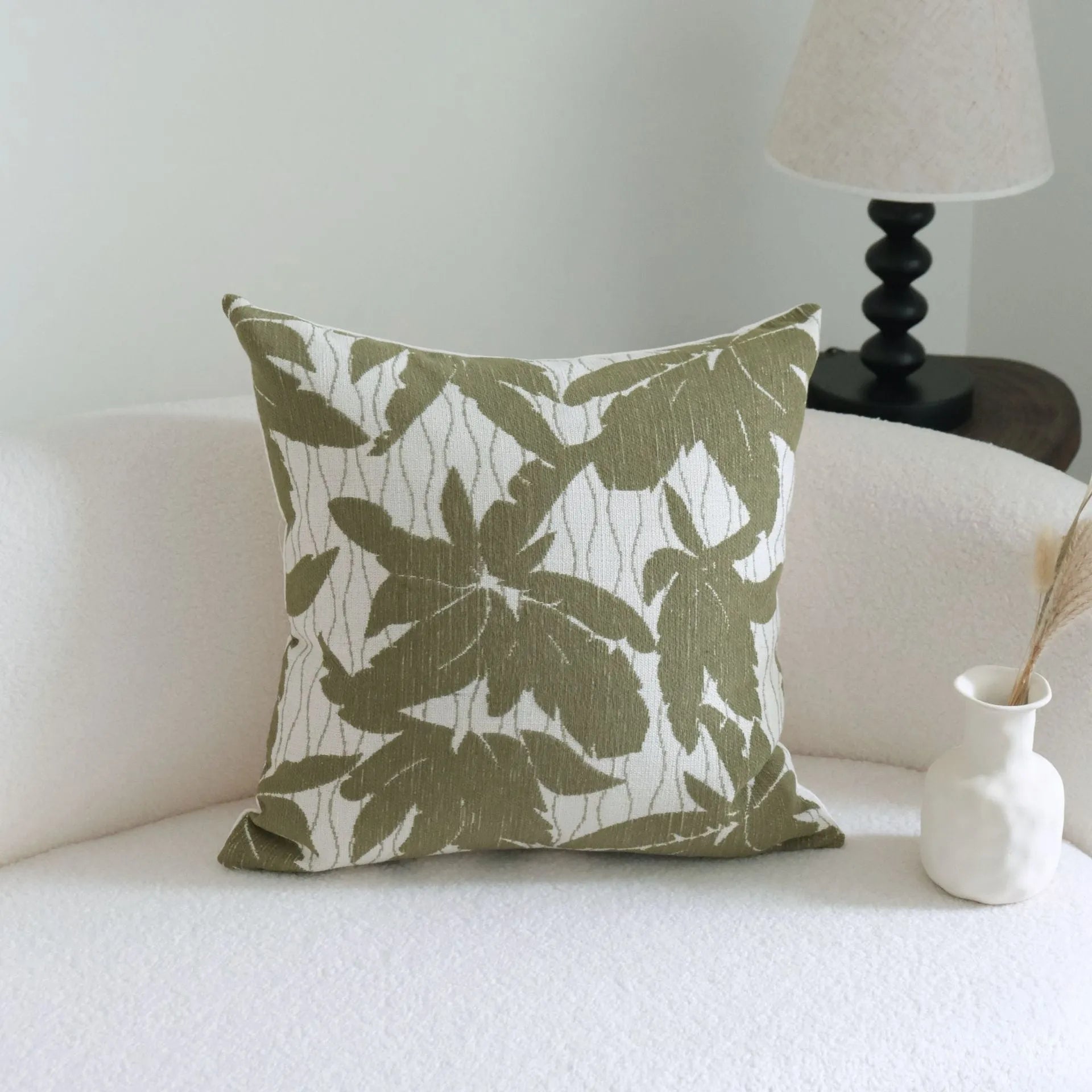 Green cotton and linen hotel pillow with striped or leaf pattern tassel detail on a bed.