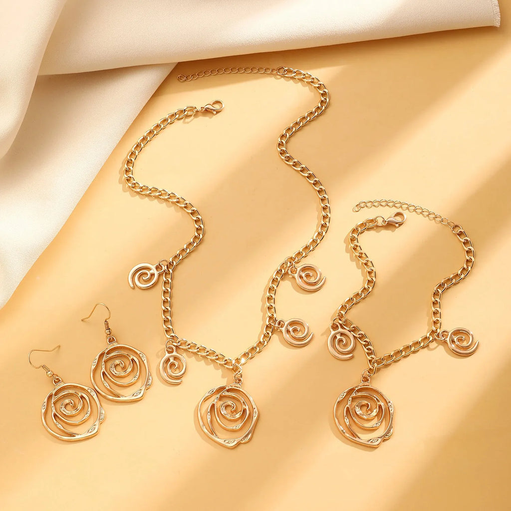 Gold tone spiral donut necklace, bracelet, and earrings set on a white background