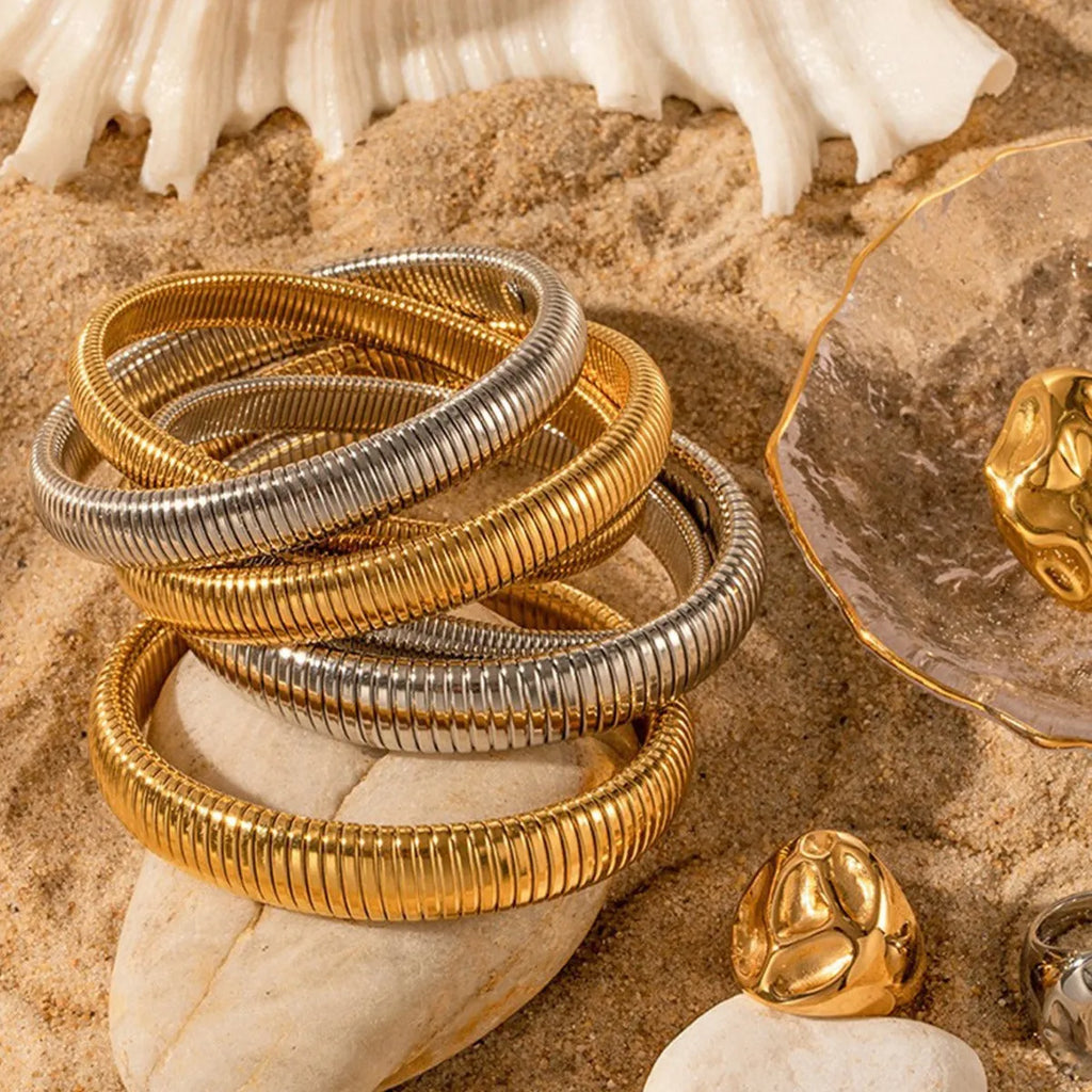 Women's gold titanium steel bracelet with exaggerated vertical stripe ring elastic pattern, showing width options.
